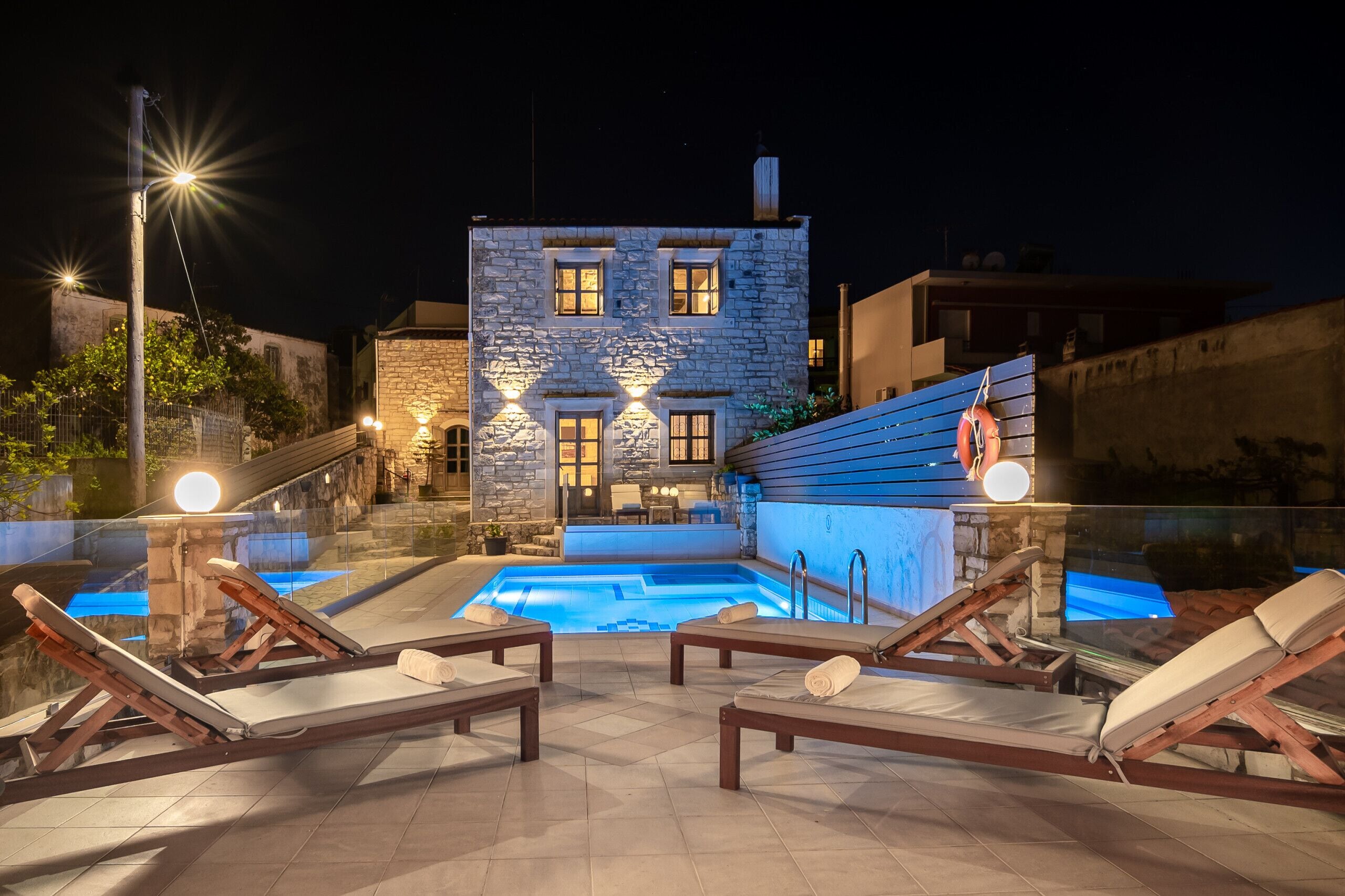 A pool area with lounge chairs and a stone building in the background.