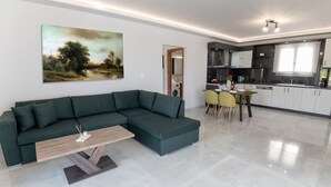 A modern living room with a sectional sofa, a coffee table, and a painting on the wall. - Destino Apartments (Rethymno)