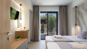 Moderni hotellihuone, jossa on suuri sänky, yöpöytä, jossa on kasvi, seinälle asennettu televisio ja liukuovesta avautuva näkymä ulos.