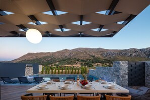 An outdoor dining area with a table set for four, overlooking a mountainous landscape. - Bella Vista Villa (Agios Vasileios)