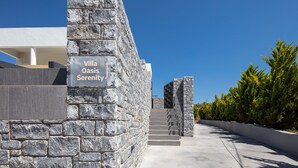 Eine Steinmauer mit einem Schild, auf dem "Villa Oasis Serenity" steht, führt zu einer Treppe.