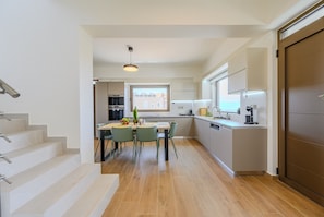 Eine moderne Küche mit Essbereich, Holzboden und einer Treppe zu einer weiteren Ebene.