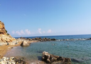 A rocky beach with clear water and a cliff. - Nevelo Villas (Rethymno)