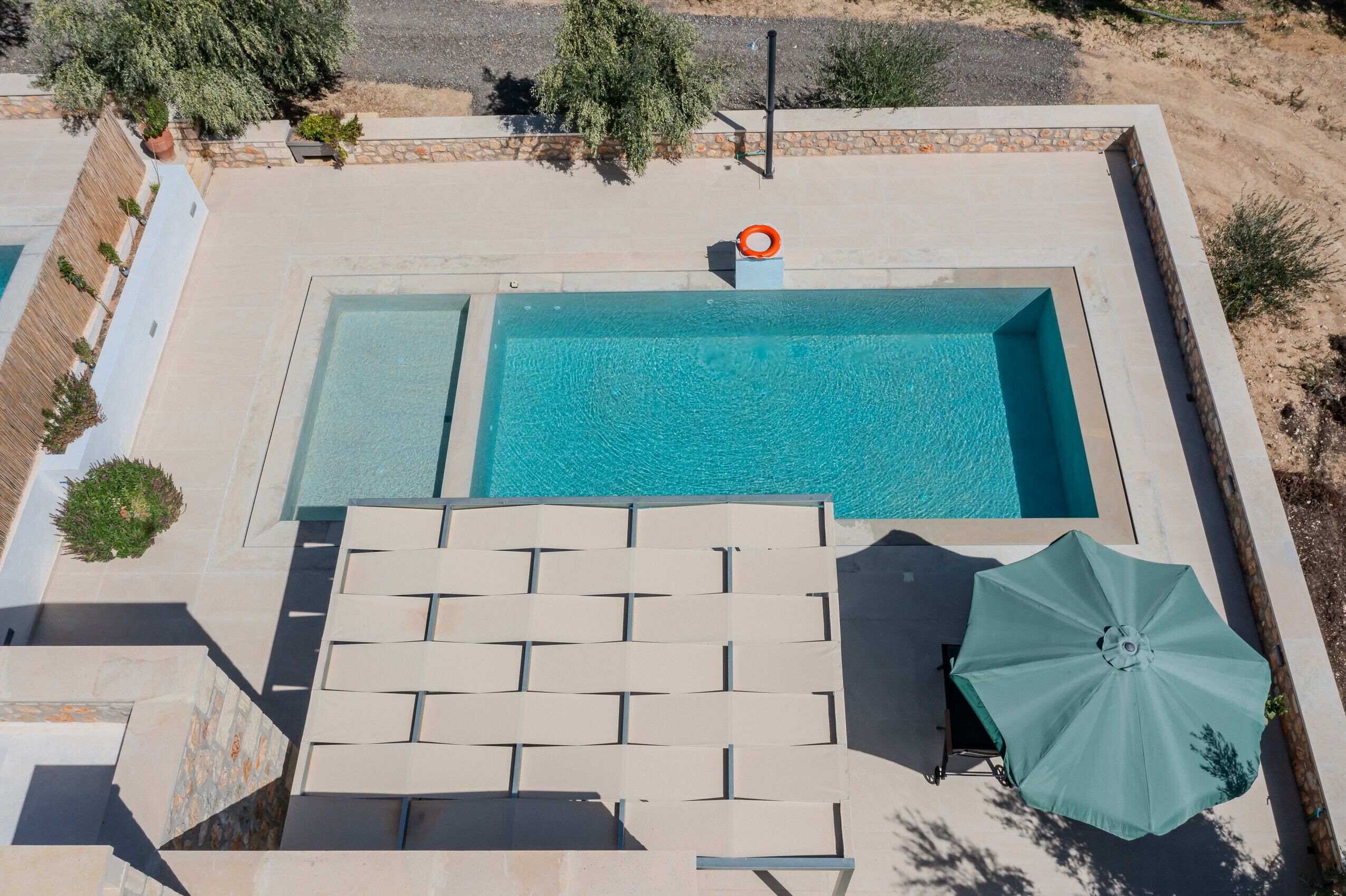 A rectangular swimming pool with a lifebuoy, lounge chairs, and an umbrella.