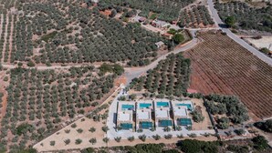 An aerial view of a property with multiple swimming pools, olive groves, and a road. - Melidoni Villas (Mylopotamos)