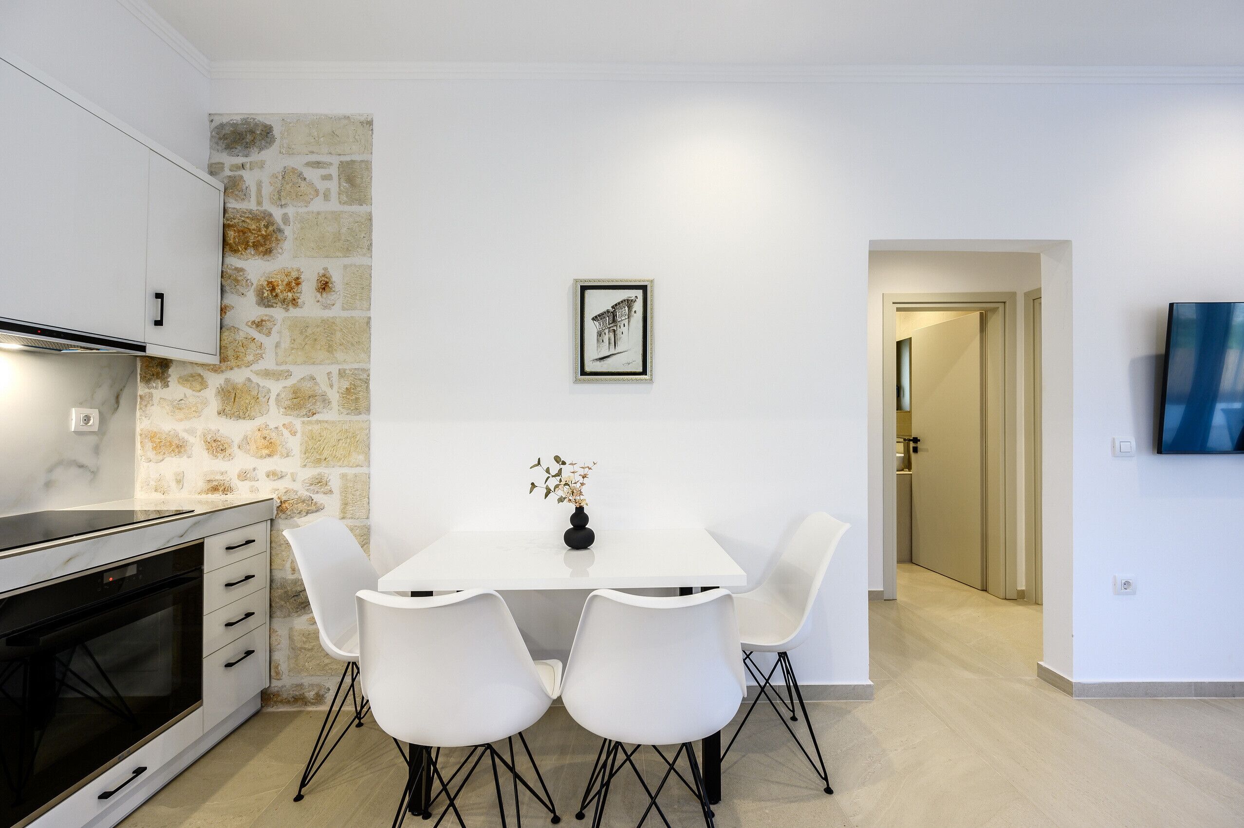 Une cuisine moderne avec des armoires blanches, un four encastré et un mur d’accent en pierre.