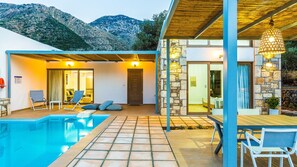 A modern villa with a swimming pool, stone walls, and a view of mountains. - Lemoni Villa (Mylopotamos)