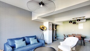 A modern living room with a blue sofa, a white armchair, a round table, and a floor lamp.