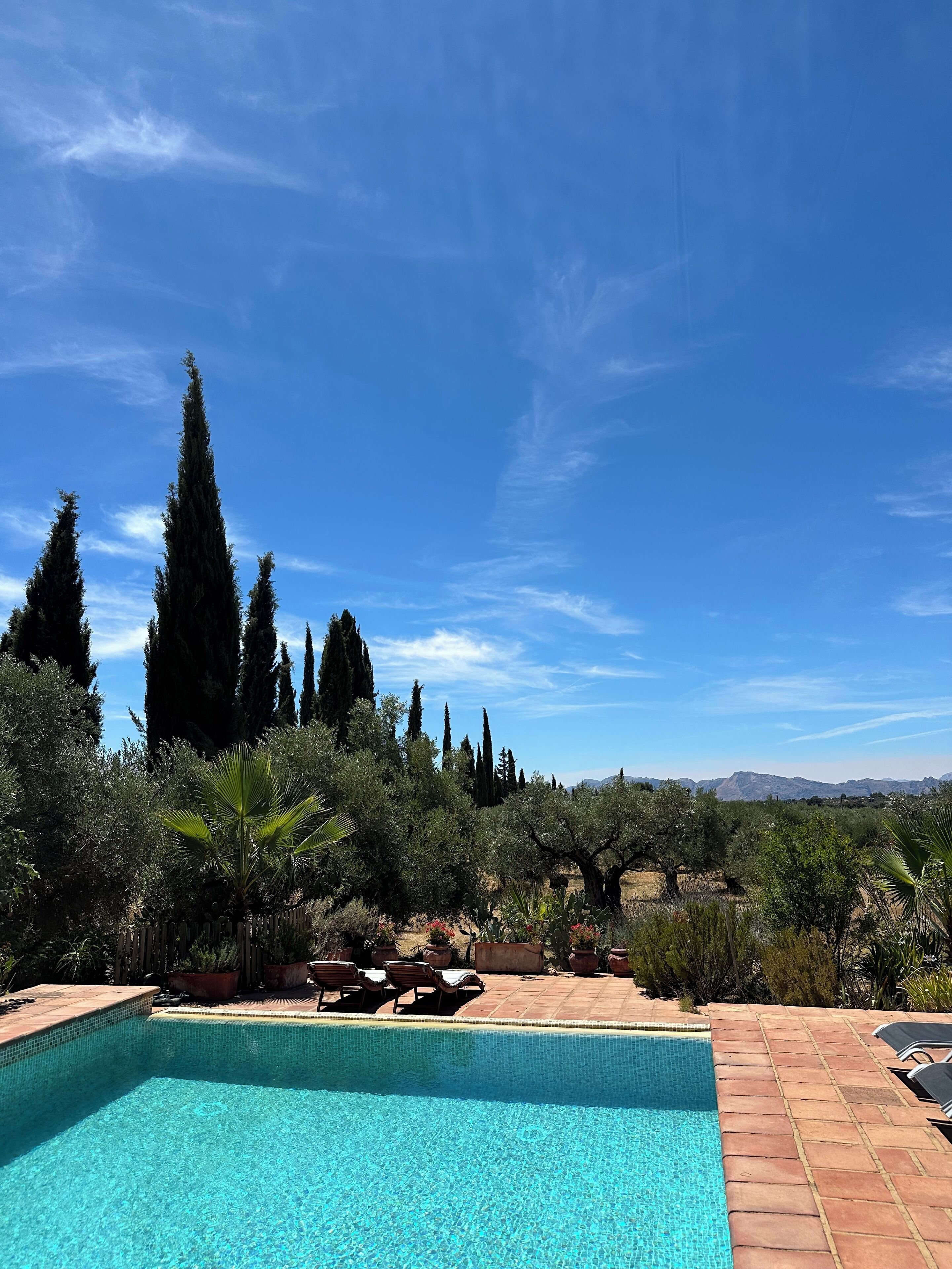 A swimming pool with lounge chairs and a view of a mountainous landscape.