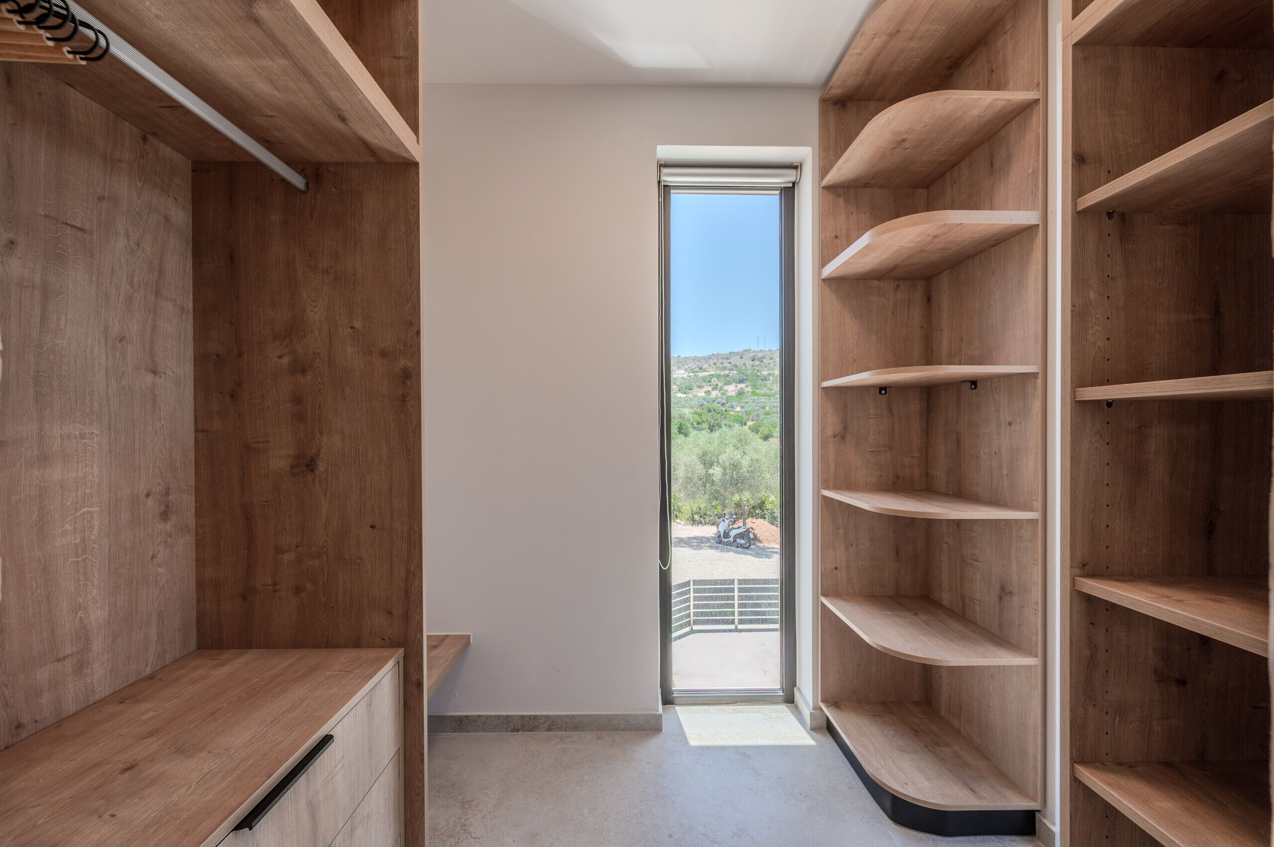 A modern interior with wooden shelving units and a view of a mountainous landscape through a glass door.