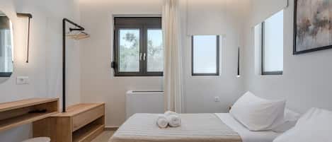 Une chambre moderne avec deux lits, un bureau en bois, une chaise et une grande fenêtre.