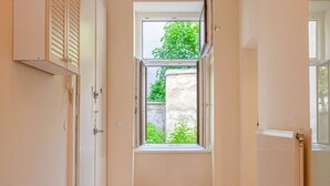 A narrow hallway with a window leading to a garden, a radiator, and a door with a cabinet. - Modern 2BR Apt. Perfect for Long and Short Stays (Wien)
