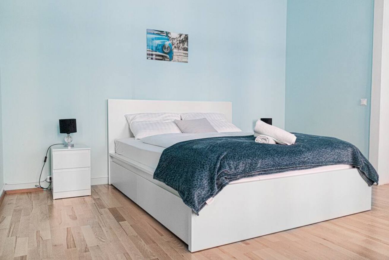 Une chambre à coucher avec un lit, des tables de chevet, une lampe et un tableau accroché au mur.