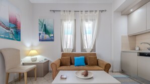 A modern living room with a sofa, a dining table, and a kitchen area. - Aloe (Rethymno)