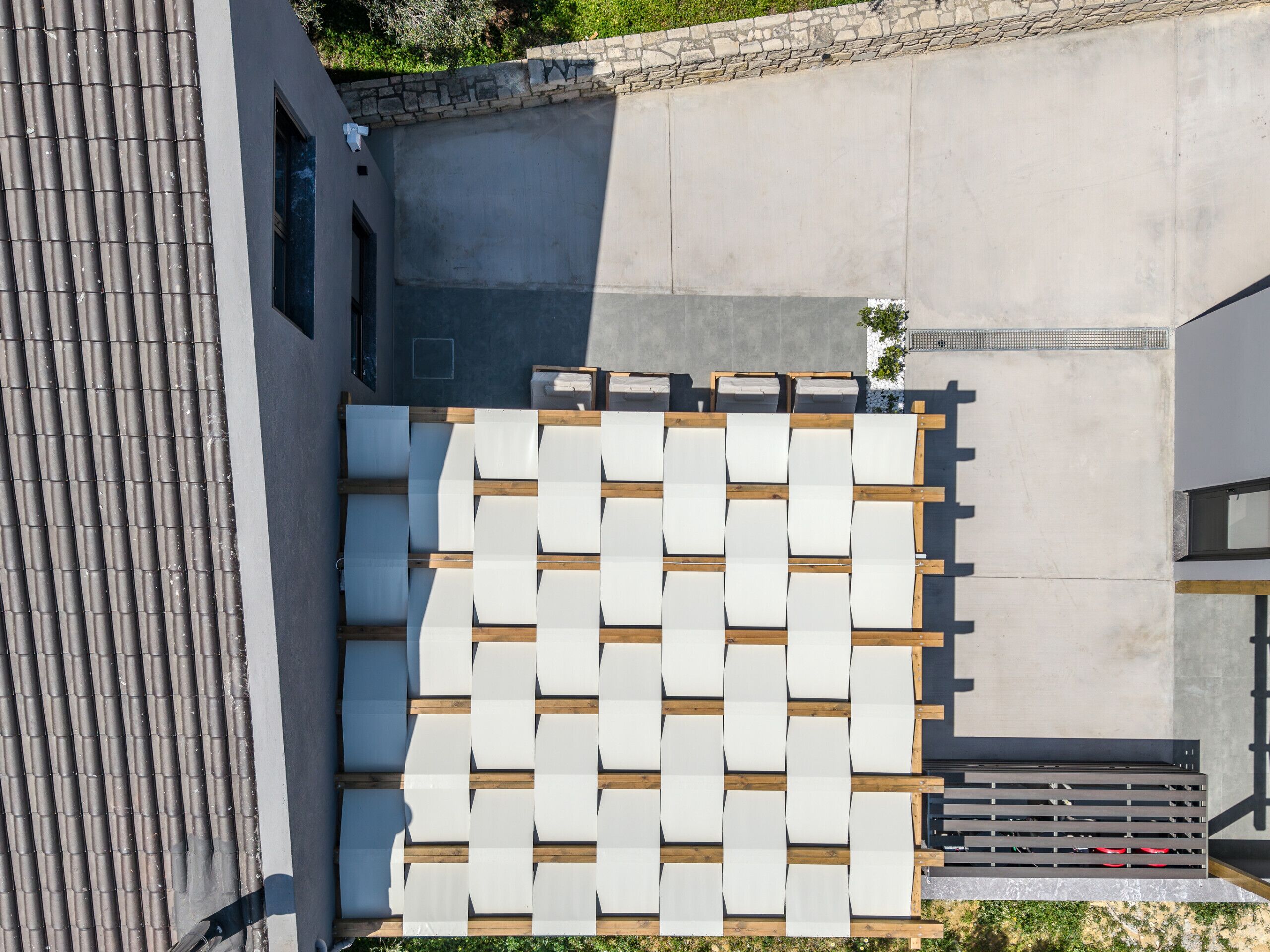 A modern outdoor seating area with a concrete wall and a wooden deck.