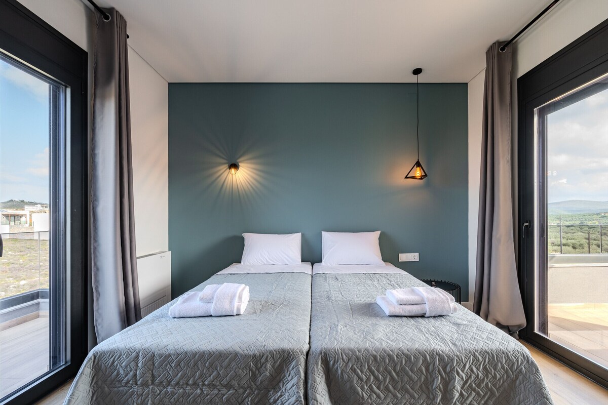 A hotel room with two beds, a large window, and a view of the landscape.