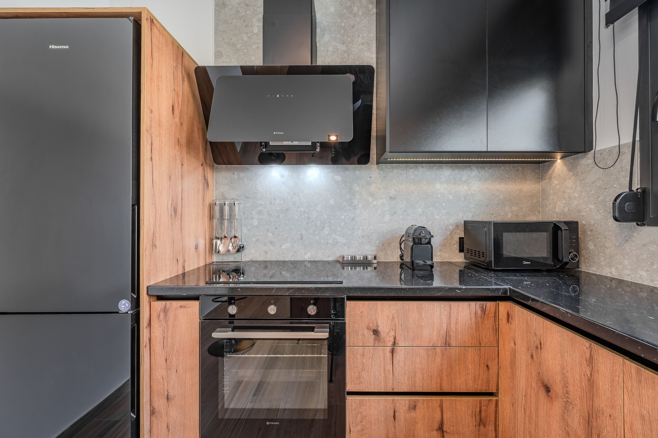 A compact kitchen with a refrigerator, oven, microwave, and wooden cabinets.