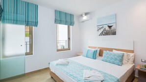 A bedroom with a large bed, two windows with curtains, a painting of a dock, and a wooden floor. - Sugar Premium Villa (Mylopotamos)