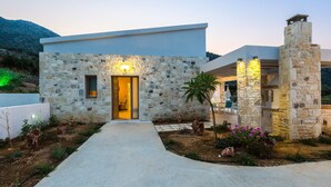 A modern stone house with a paved entrance, a visible door, and a stone chimney. - Sugar Premium Villa (Mylopotamos)