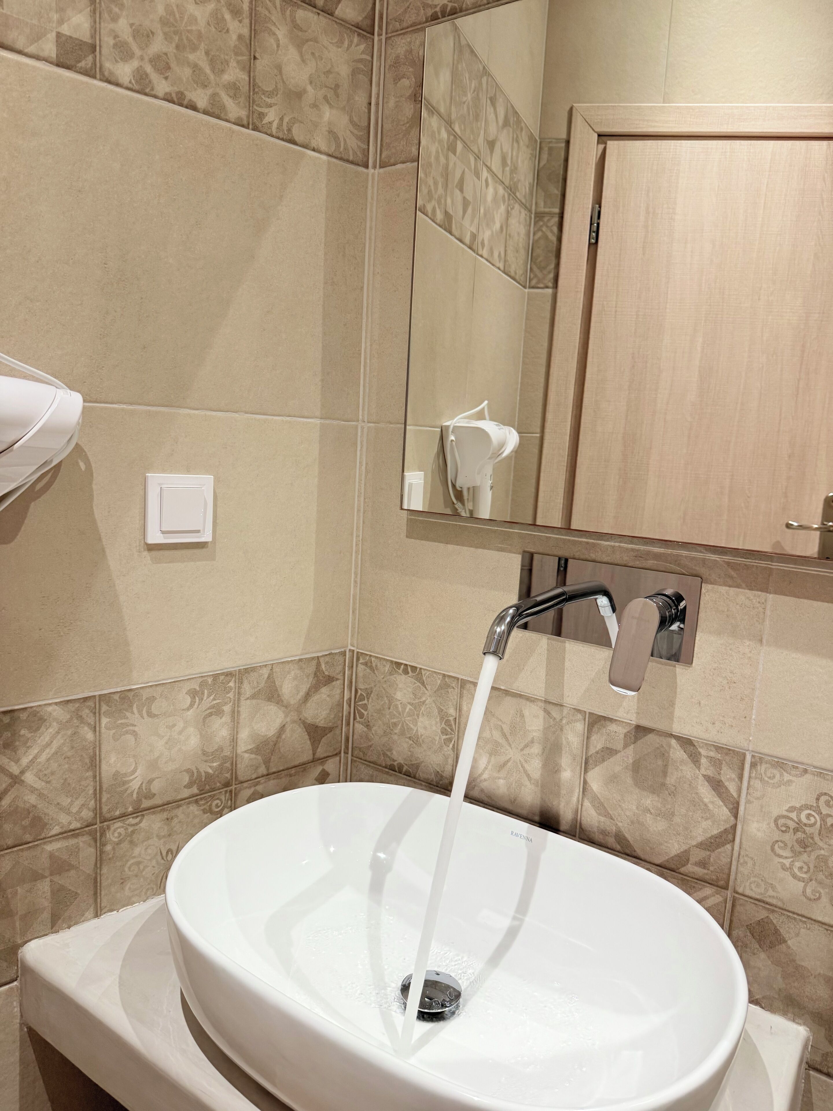 Un baño con lavamanos blanco, un espejo y un perchero para toallas.