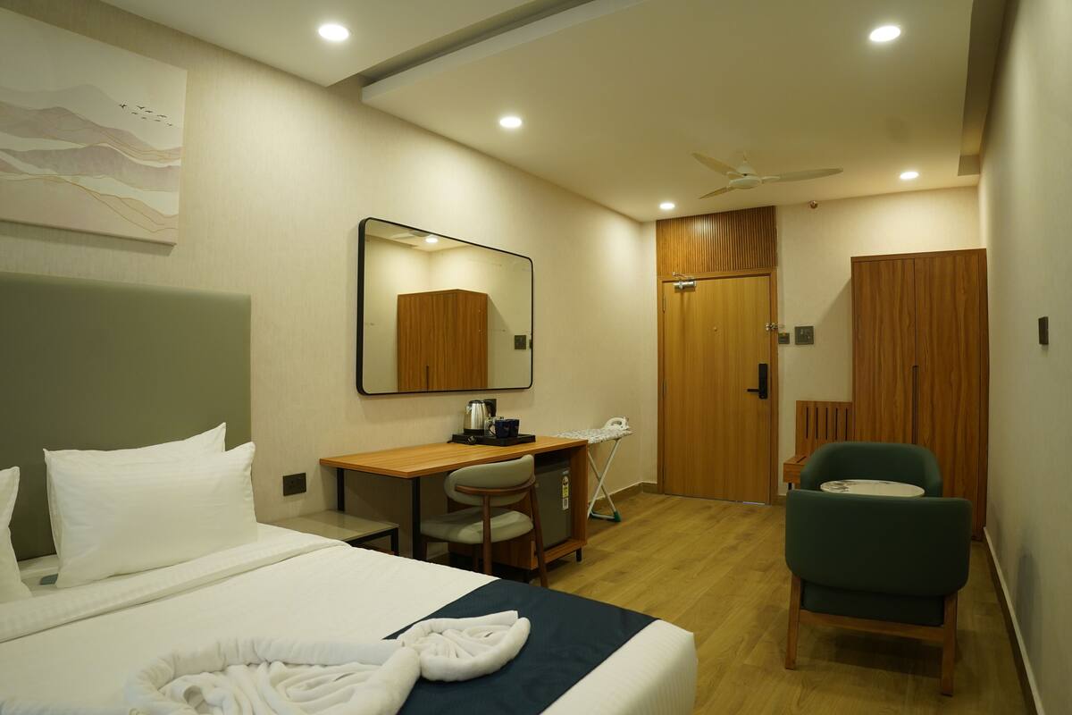 Une chambre d’hôtel avec un lit, un bureau, une chaise et un miroir.