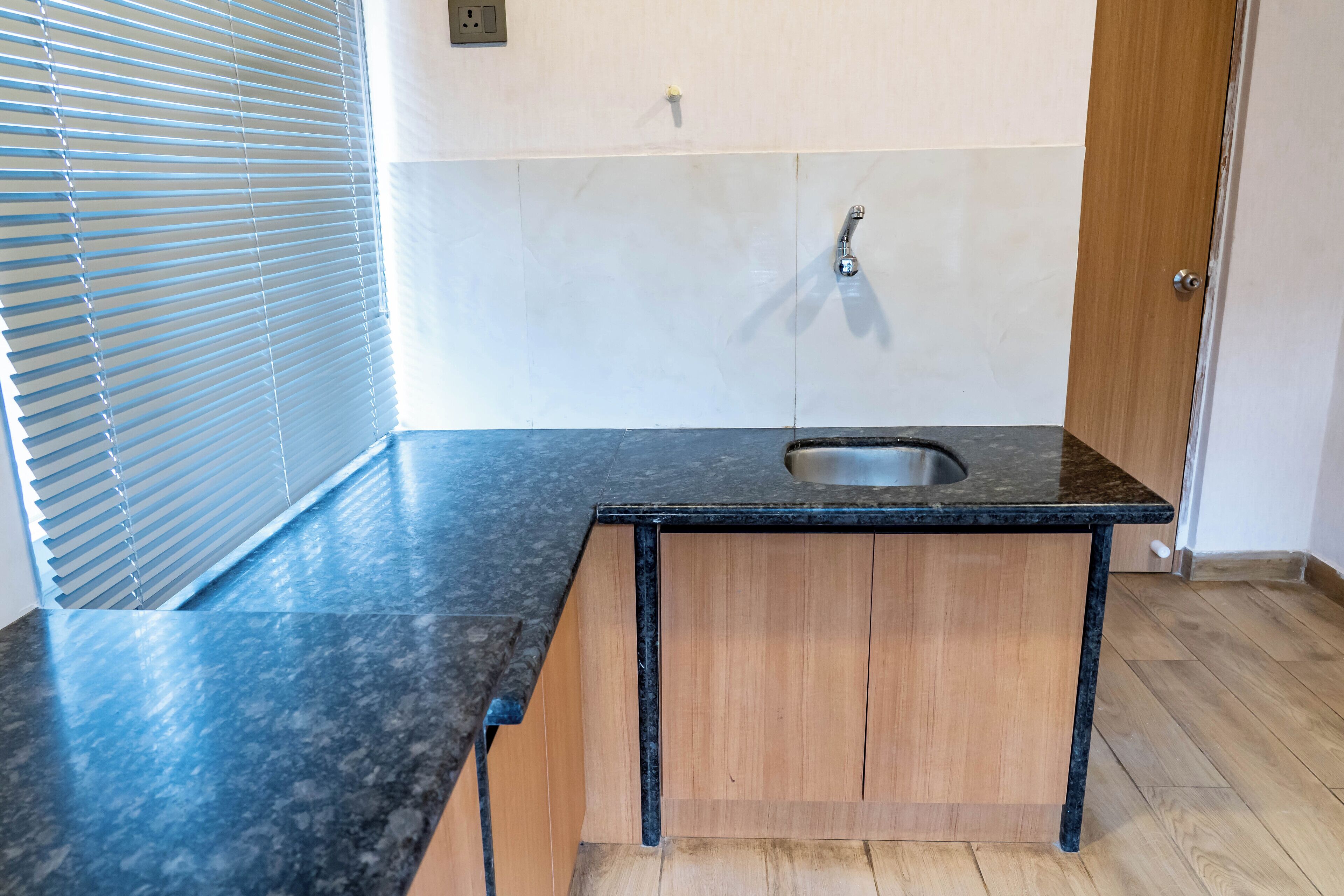 A kitchen with a black countertop, wooden cabinets, and a stainless steel sink.
