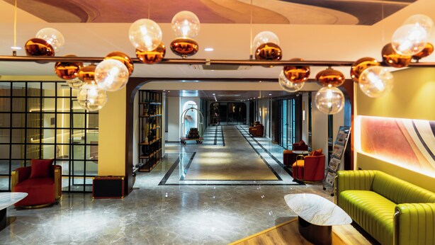 Vestíbulo de hotel con un pasillo central, zonas de estar y un mostrador de recepción.