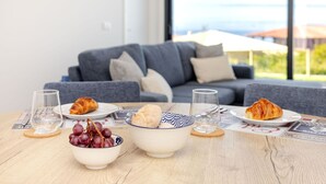 Ett matbord med croissanter, vindruvor och en skål med grädde. På bordet står glas och en meny.