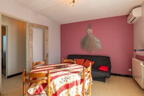 Une pièce comprenant une table à manger, des chaises, un canapé et un climatiseur fixé au mur.