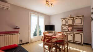 Een kamer met een bed, een eettafel met stoelen, een televisie en een kast.