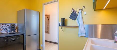 A compact kitchen with a refrigerator, dishwasher, and coffee machine.