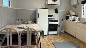 Una cocina compacta con refrigerador, estufa, microondas y un reloj en la pared.