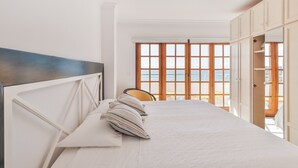 A bedroom with a bed, a chair, and a view of the sea through large windows. - Apartment 'Playa Delphin 403' with Sea View, Balcony and Wi-Fi (Puerto de Naos)