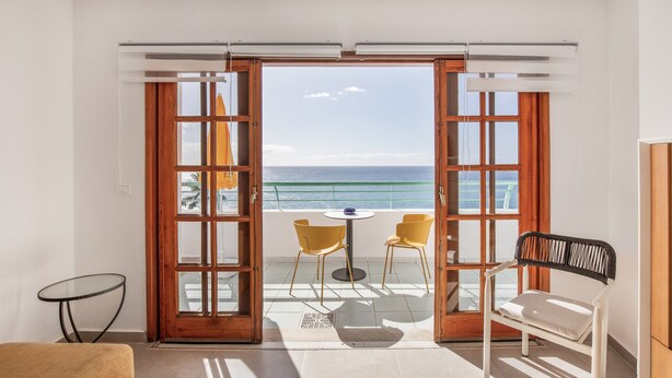 A room with a balcony, a table with chairs, and a view of the sea. - Apartment 'Playa Delphin 403' with Sea View, Balcony and Wi-Fi (Puerto de Naos)