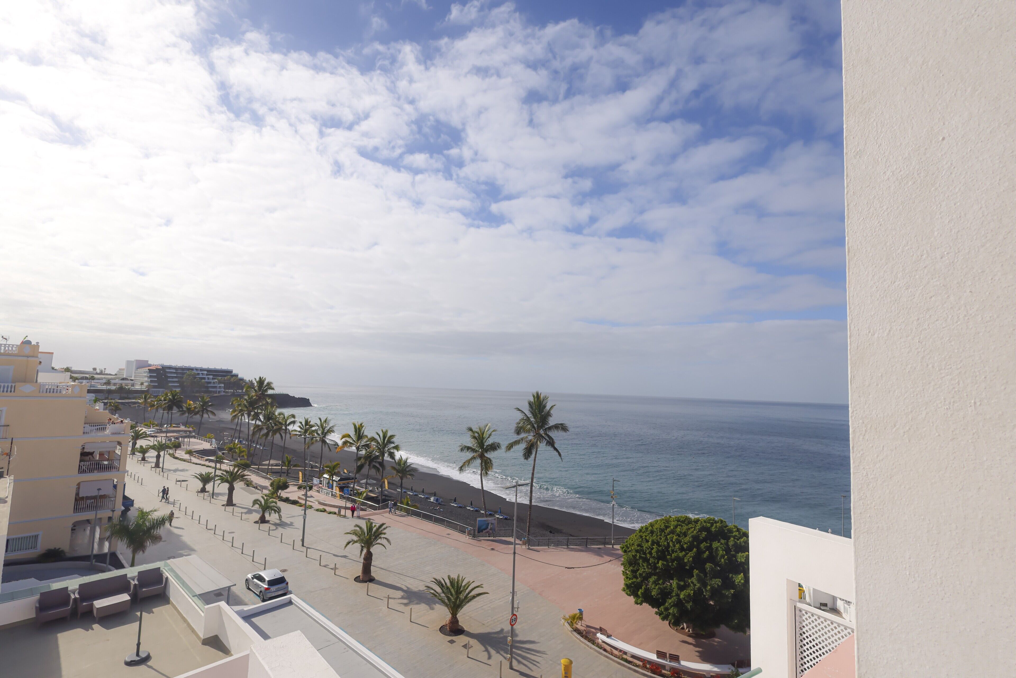Blick auf die Küste mit Strand, Palmen und Gebäuden.