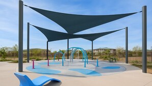 A playground with blue and pink play structures, surrounded by a shaded area with a curved bench. - BRAND NEW Comfy Guest House in a Great Location (Henderson)