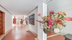 A hallway with a glass table holding a floral arrangement, a lamp, and a painting on the wall. - Apartment 'Playa Delphin 105' with Sea View, Balcony and Wi-Fi (Puerto de Naos)