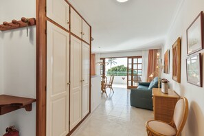 Ein Zimmer mit Kleiderschrank, Sofa, Sessel, Tisch und einem Balkon mit Aussicht.