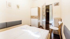 Une chambre d’hôtel comprenant un lit, une chaise, une armoire et une porte donnant sur un couloir.