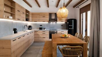 Una cocina moderna con armarios de madera, una isla central y un comedor con sillas de mimbre.