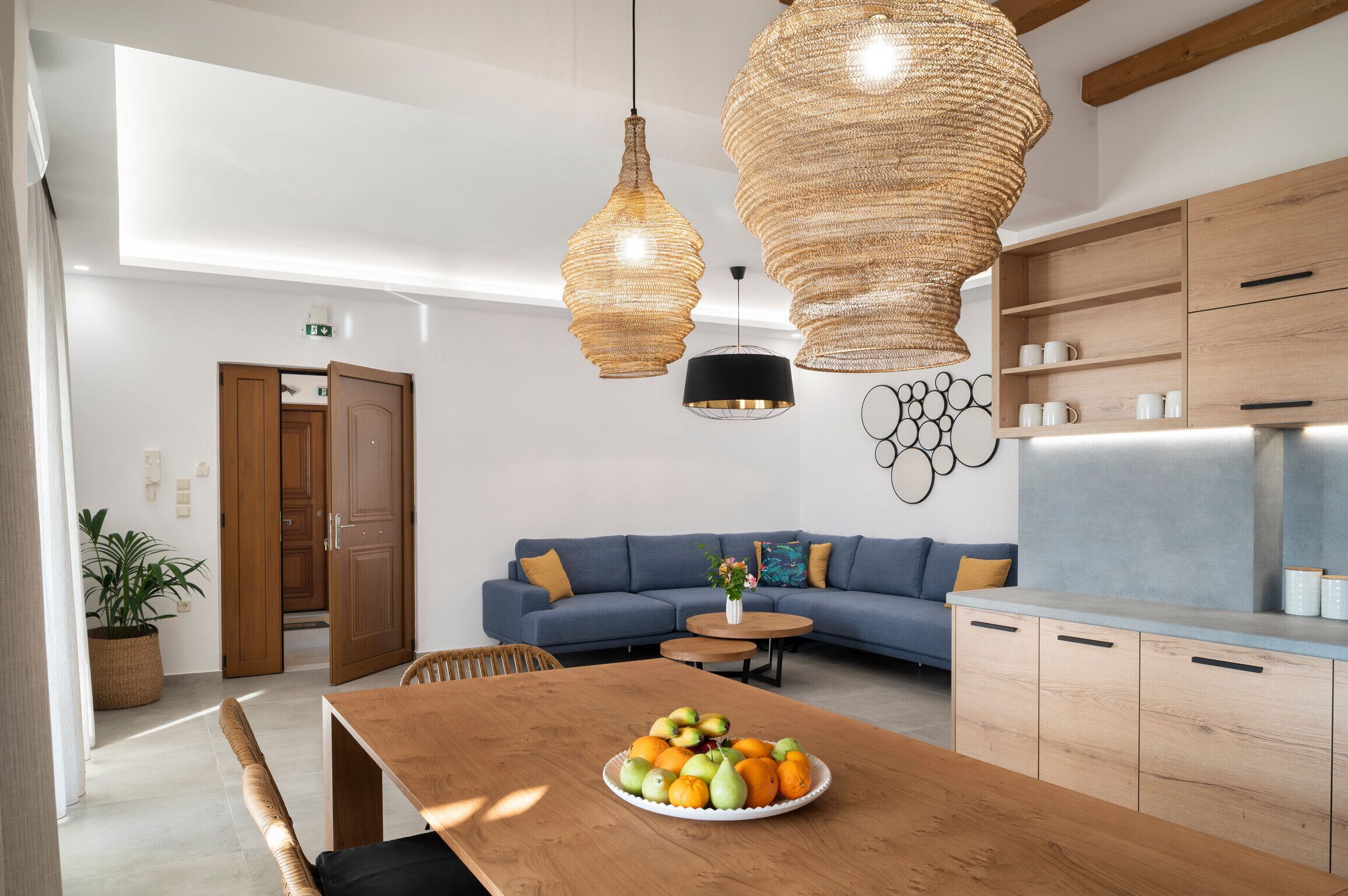 Una cocina moderna con armarios de madera, una mesa de comedor con un frutero y un sofá azul.