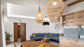 A modern kitchen with wooden cabinets, a dining table with a fruit bowl, and a blue sofa. - Zen Luxury Home (Rethymno)