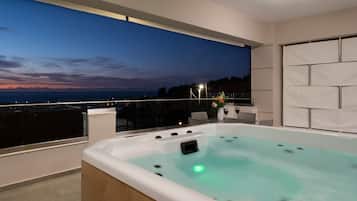 Un moderno jacuzzi interior con vista al océano al atardecer.