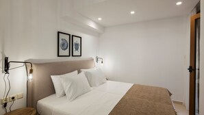 Un dormitorio con cama, mesita de noche, lámpara de pared y cuadro enmarcado.