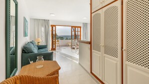 A room with a sofa, a table, a mirror, and a view through a door to an outdoor area. - Apartment 'Playa Delphin 302' with Sea View, Balcony and Wi-Fi (Puerto de Naos)