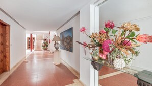 A hallway with a glass display case containing flowers, a lamp, and a painting on the wall. - Apartment 'Playa Delphin 302' with Sea View, Balcony and Wi-Fi (Puerto de Naos)