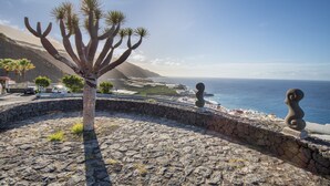 A coastal landscape with a cactus, stone walls, and a statue. - Apartment 'Playa Delphin 302' with Sea View, Balcony and Wi-Fi (Puerto de Naos)