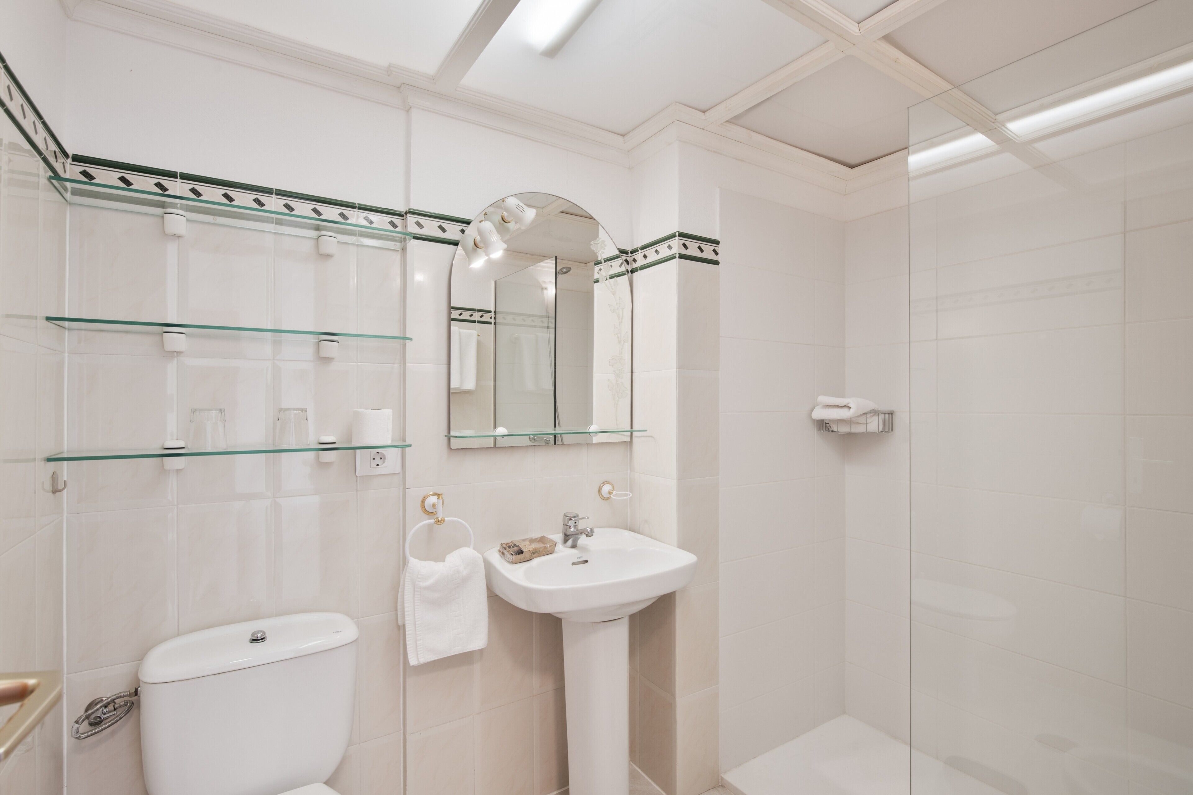 Un baño con inodoro, lavamanos y cabina de ducha de vidrio.