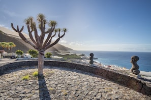 Eine Küstenlandschaft mit Kakteen, Steinmauern und einer Statue.