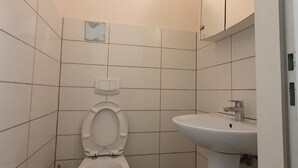Casa de banho com sanita, lavatório e paredes em azulejo.